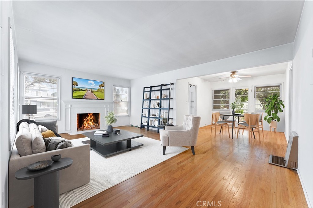 Spacious living room with hardwood floors, fireplace, TV, dining area, and large windows