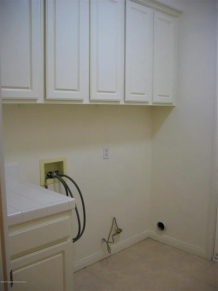 Laundry room with white cabinets, washer-dryer hookups, and clean neutral tones