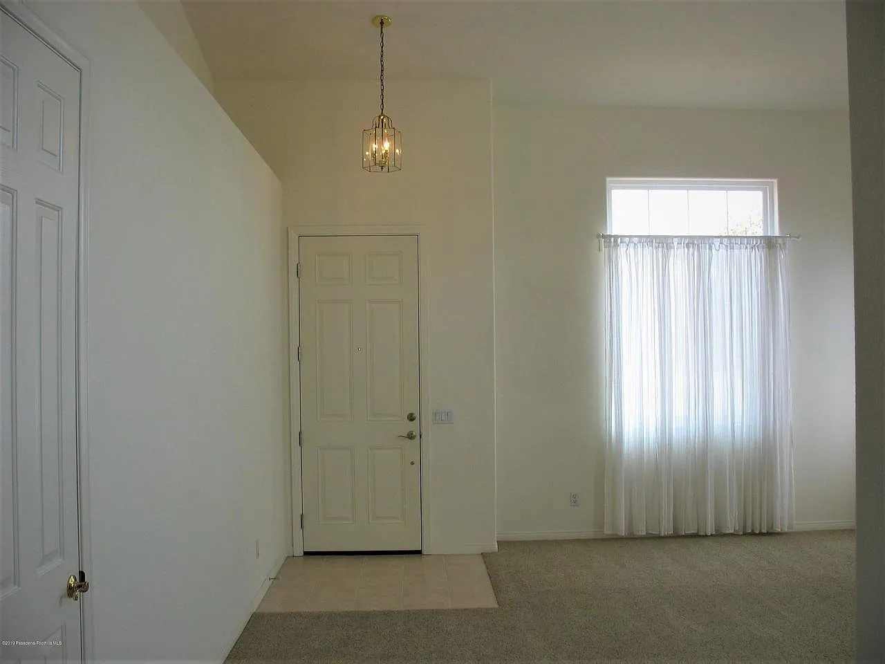 Minimalist room with white walls, closed door, carpet, and sunlit window