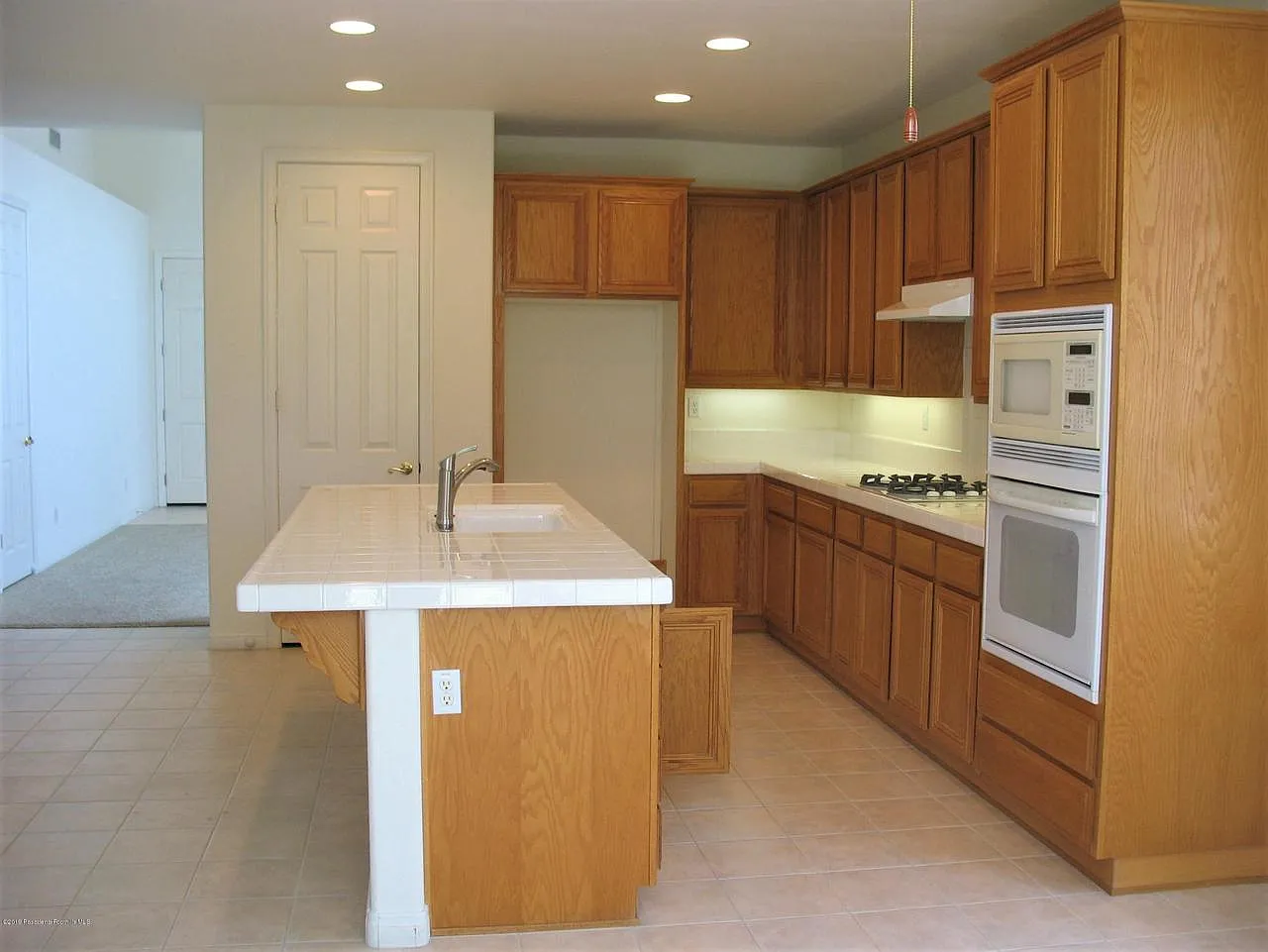 Bright kitchen with oak cabinets, tile island with sink, and built-in appliances