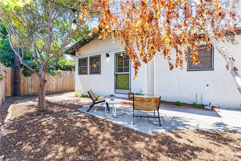 Small patio with chairs, table, birch tree, and sunlit fenced yard