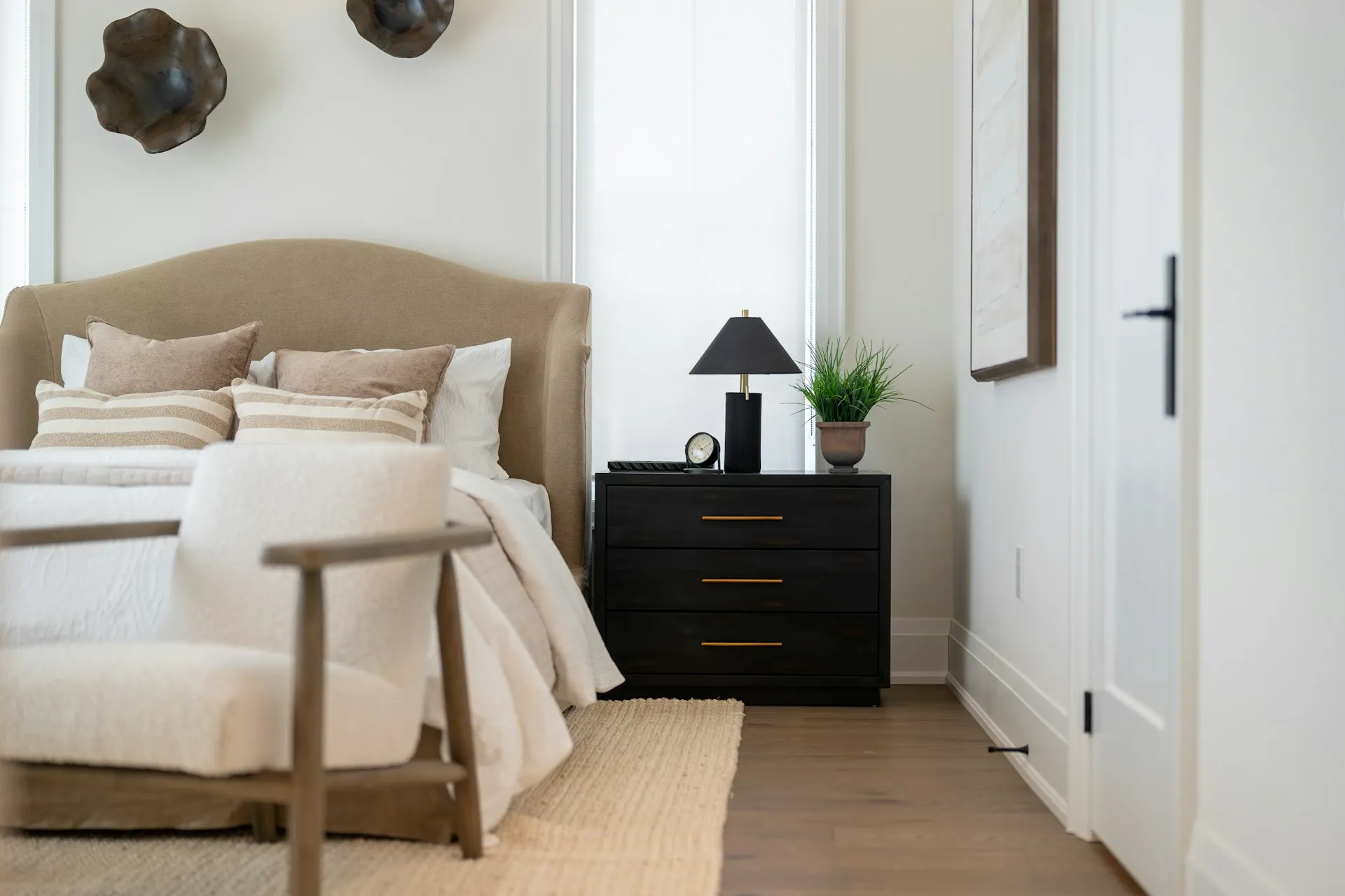 Cozy bedroom with beige headboard, striped pillows, plush bedding, and nightstand decor