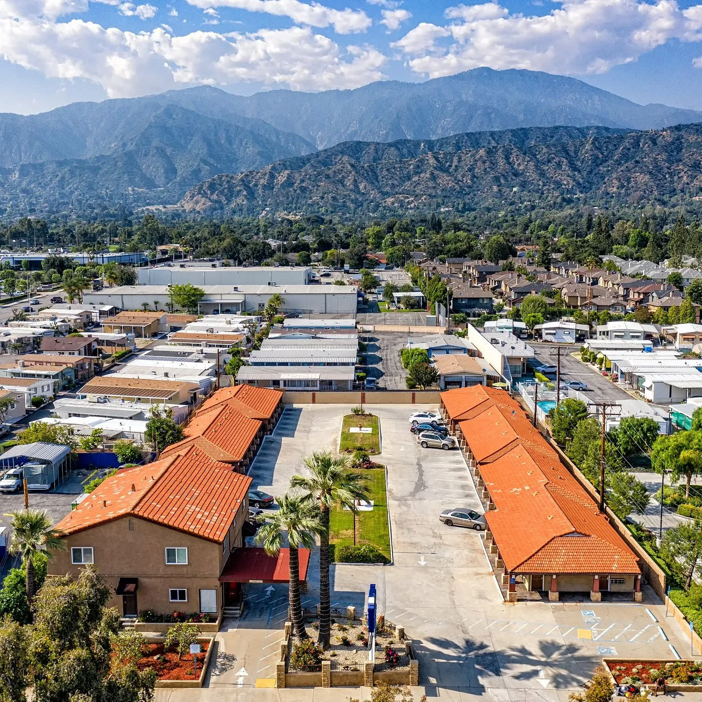 Aerial view of red-tile roof homes, palm trees, and mountains