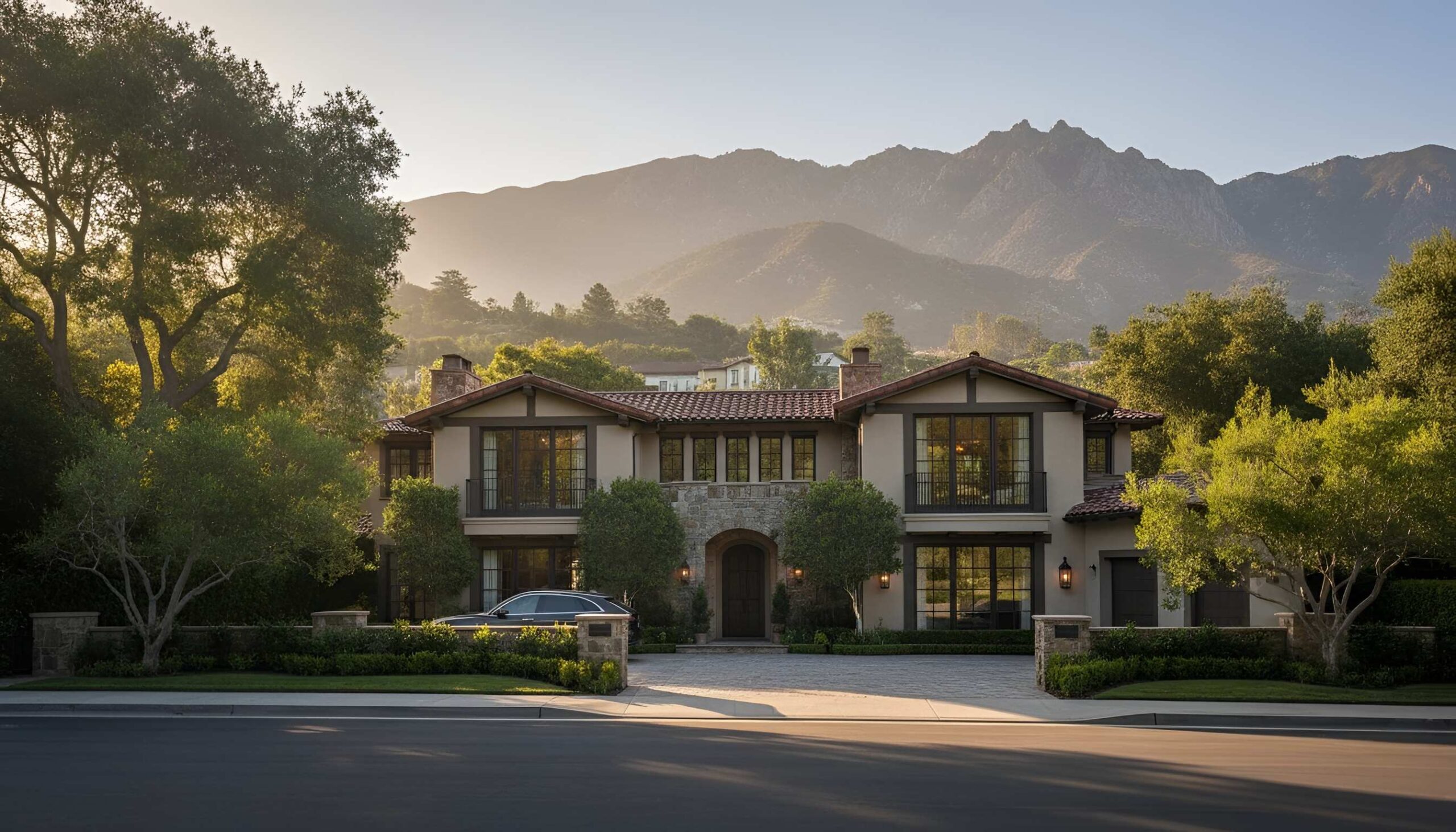 Elegant two-story home with large windows, trees, and sunlit mountain backdrop